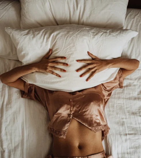 una mujer acostada en la cama con las manos sobre una almohada